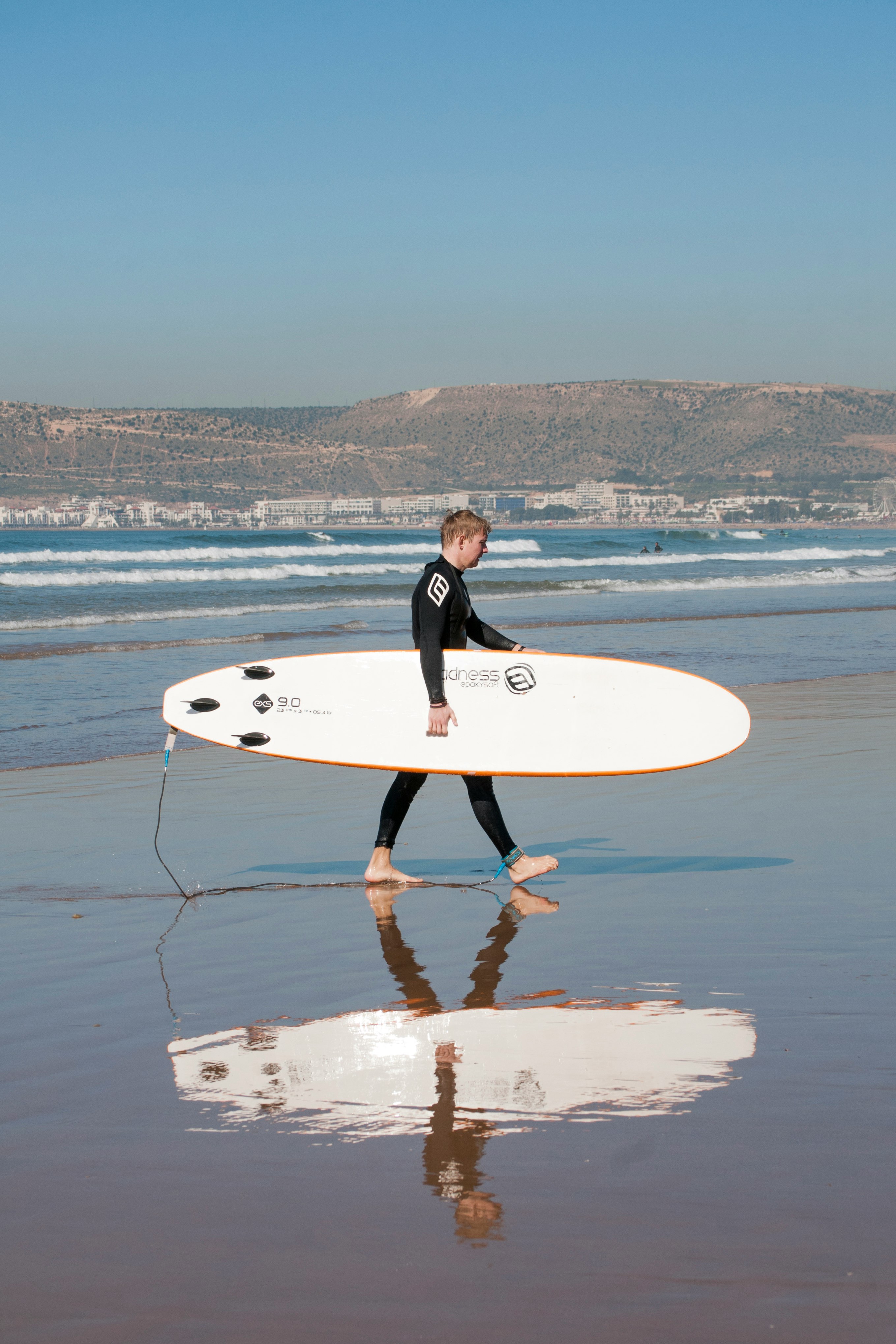 man holding surfboard while walking on shore